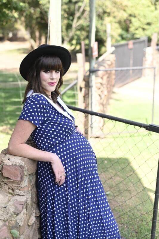 Navy and white polka dot maternity and nursing dress with Peter Pan collar, short sleeves, and hi-low silhouette