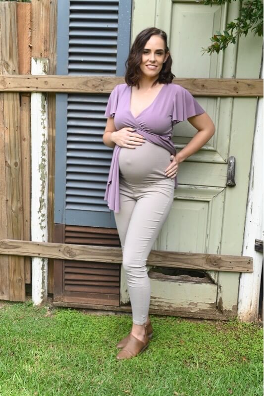 Pregnant woman wearing beige skinny maternity pants with stretchy belly band Pregnant woman wearing beige skinny maternity pants with stretchy belly band