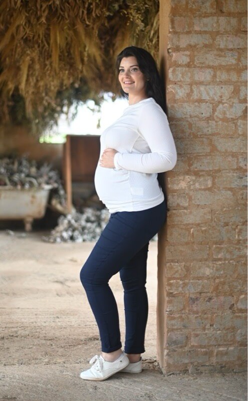 Pregnant woman wearing navy skinny maternity pants with stretchy belly band