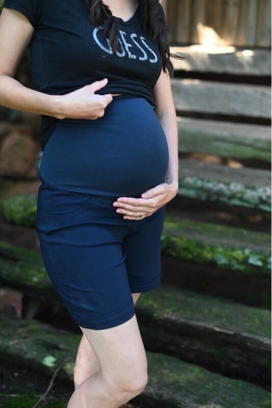 Pregnant model wearing navy maternity shorts with stretchy belly band