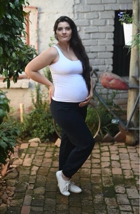 Pregnant model wearing navy straight leg maternity viscose pants with stretchy belly band