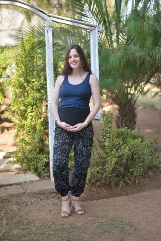 Pregnant model wearing black and blue leopard maternity viscose pants with stretchy belly band outdoors