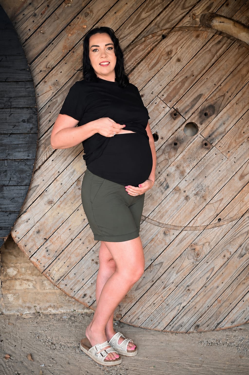 Pregnant model wearing olive maternity shorts with stretchy belly band