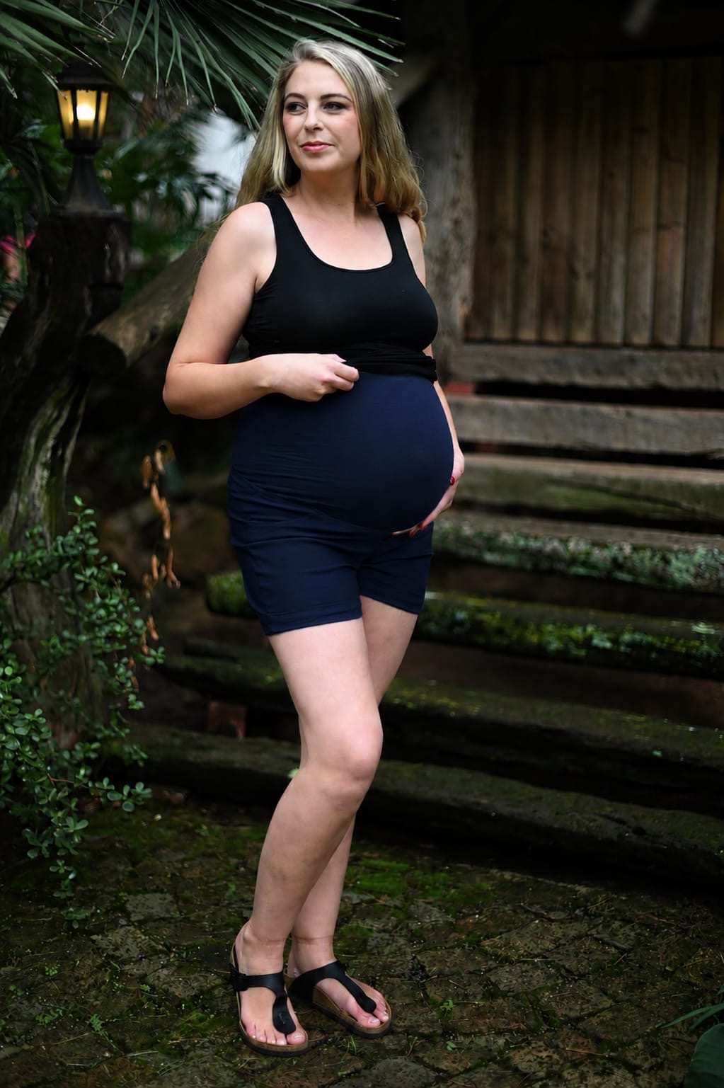 Pregnant model wearing navy maternity short shorts with stretchy belly band