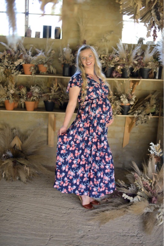 Pregnant woman wearing navy and pink floral fold over maternity nursing dress
