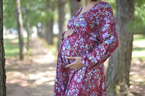 Pregnant woman wearing maroon floral fold-over maternity nursing dress