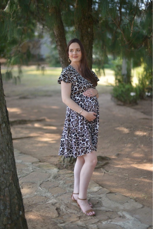 Pregnant woman wearing white leopard print button-up maternity nursing dress