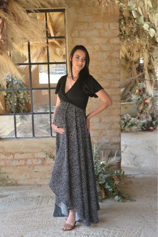 Pregnant woman wearing black and white polka dot fold-over maternity nursing dress